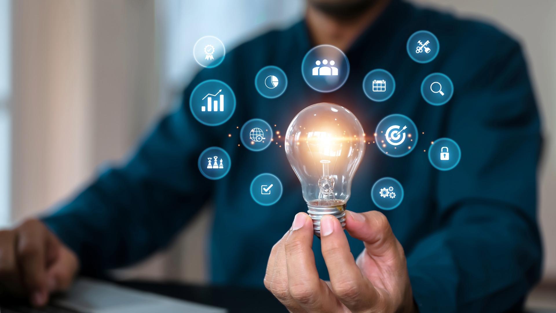 Close-up of a person holding a light bulb, surrounded by icons representing services.