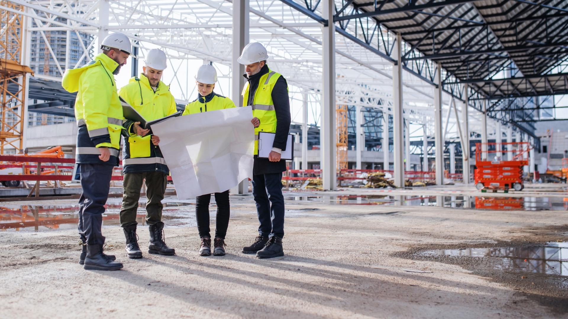 Four people examining drawings at a construction site.